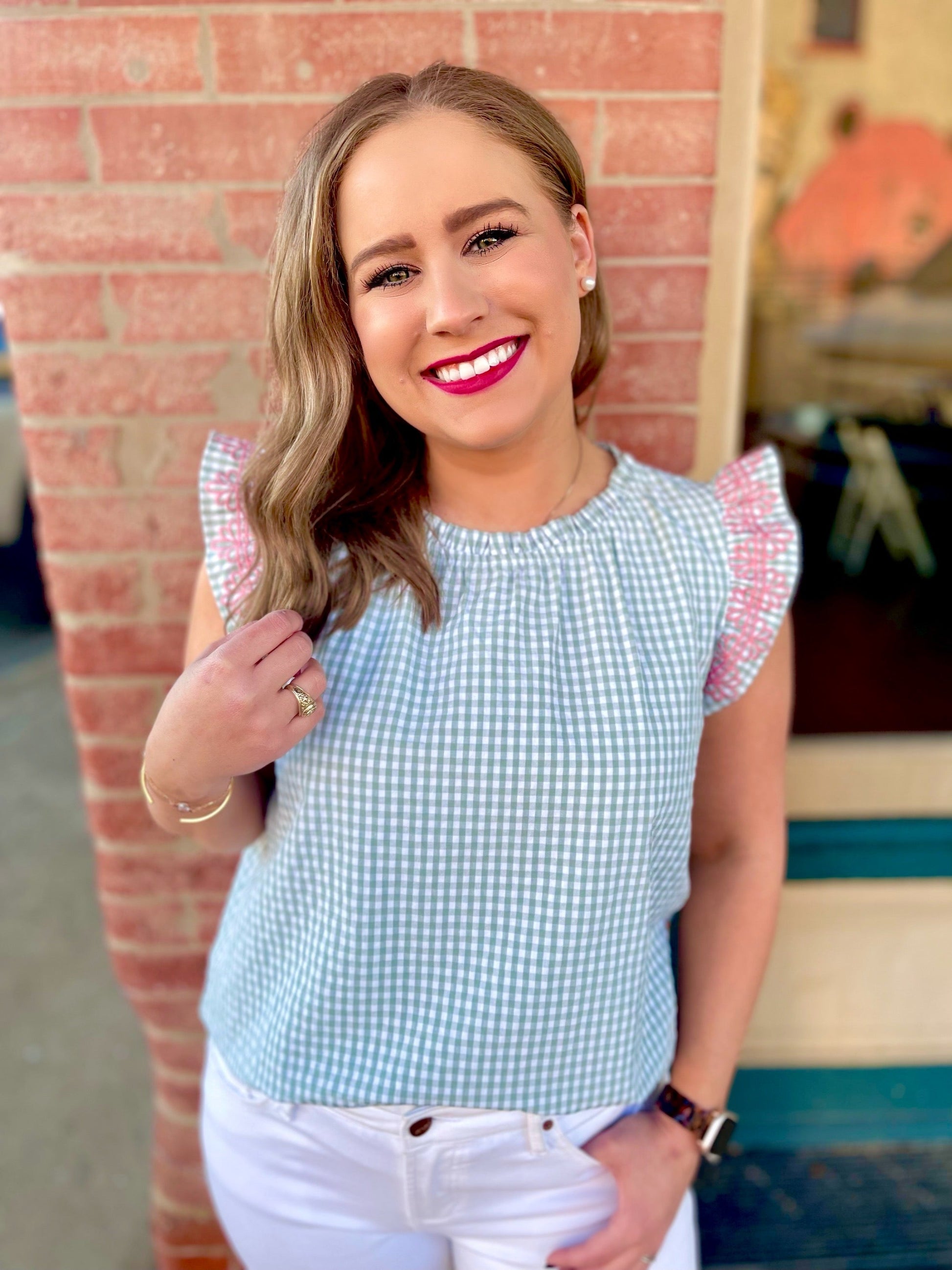 The Audrey Top by Washco Apparel is a beautiful mint green and white gingham print with a pop of pink embroidery design. We love the gathered neckline and ruffled flair sleeves. Pair the Audrey Top with a cardigan or cute denim jacket and make it a great top for year round!