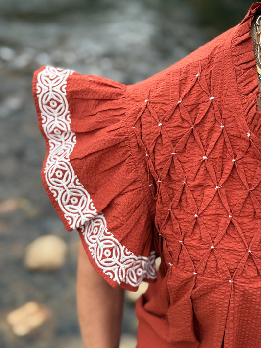 Orange top with smocked and embroidery detailing by Washco Apparel