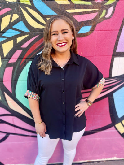 The Britton Top by Washco Apparel is fun, unique and can be styled so many ways! We love the pop of beautiful embroidery design on the black sleeves and that it is an oversized button down top with small slits on the sides.