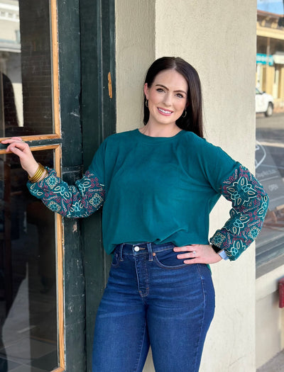 Stay warm, cozy and cute in the Cayce top by Washco Apparel! The Cayce top includes a soft sweatshirt fabric with colorful embroidered sleeves.