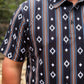 Person wearing a patterned shirt with vertical stripes and geometric designs.