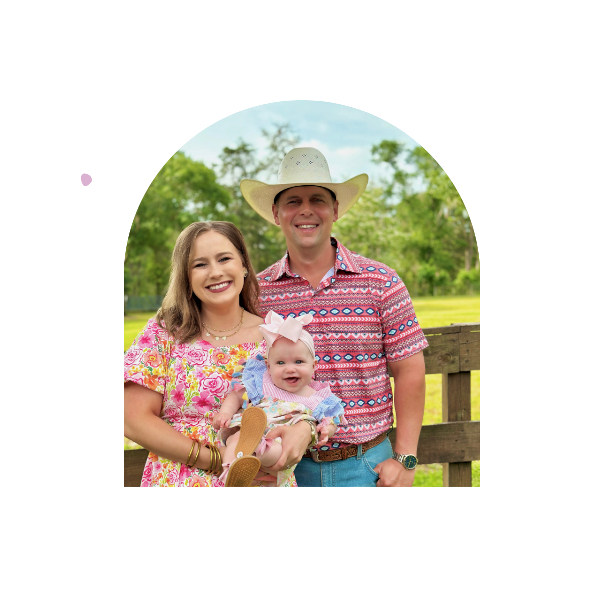 Family of three outdoors with a man wearing a cowboy hat, woman, and baby.