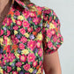 Colorful floral patterned shirt worn by a person on a plain background
