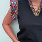 Black top with colorful floral shoulder pads against a light background