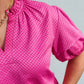 Close-up of a bright pink textured top with a blurred background