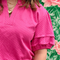 Person wearing a pink blouse with ruffled sleeves against a floral background