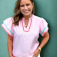Woman wearing a pink blouse with colorful trim against a teal background