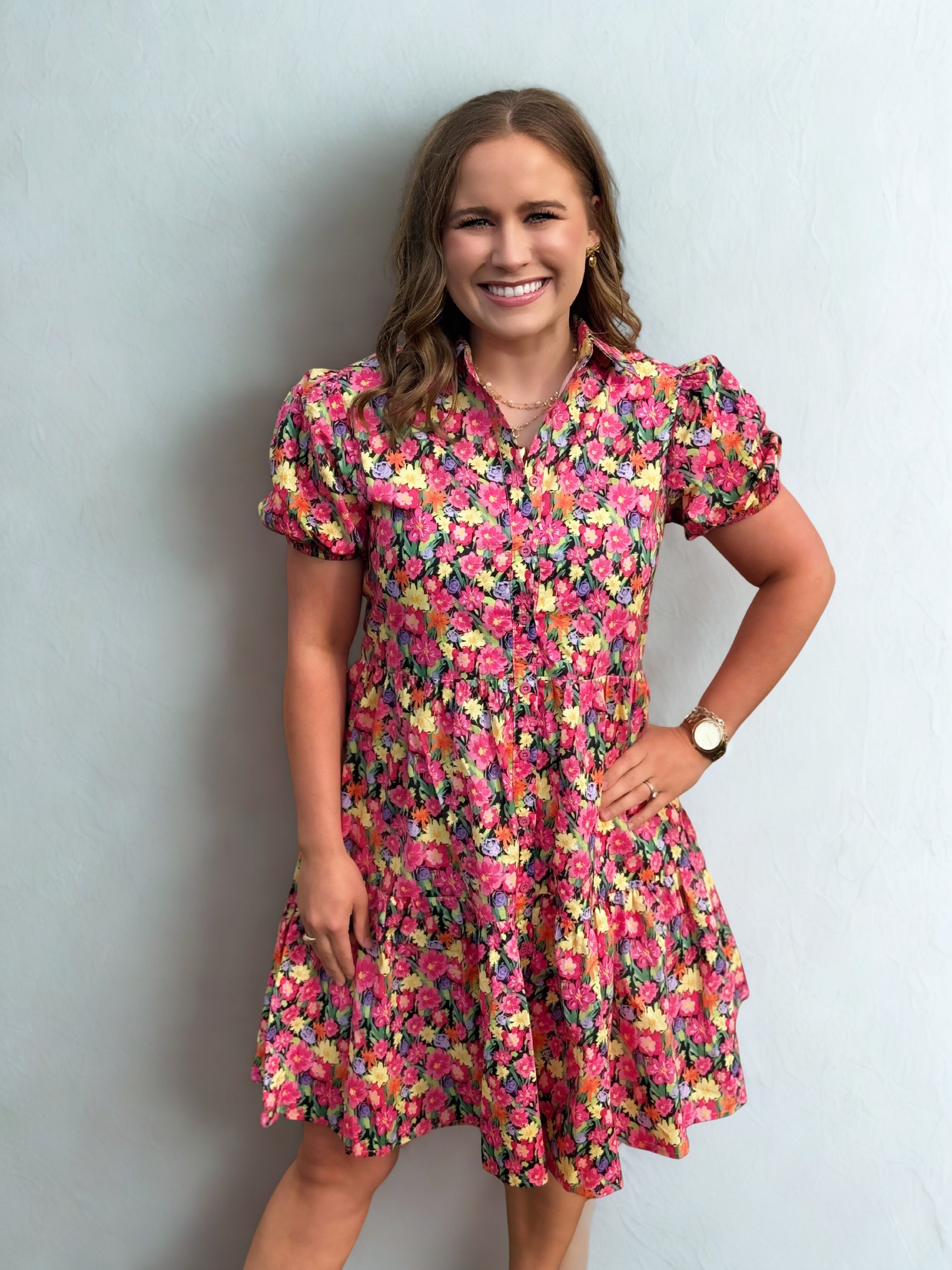Woman wearing a colorful floral dress against a plain background